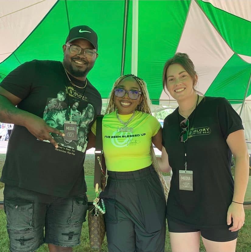 Two members of Glory in the Beat's media team with an artist at a festival.